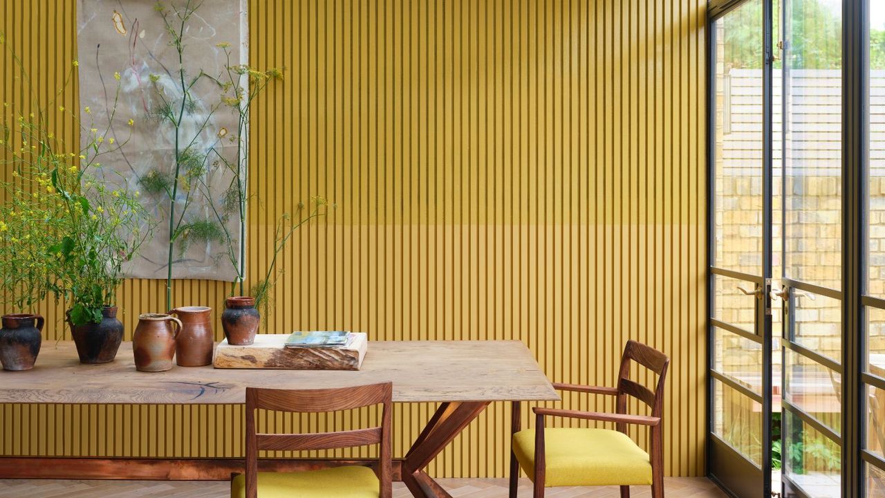 A yellow panelled kitchen with large wooden table and chairs and french doors to garden