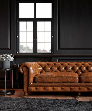 Black room with black rug and brown leather sofa