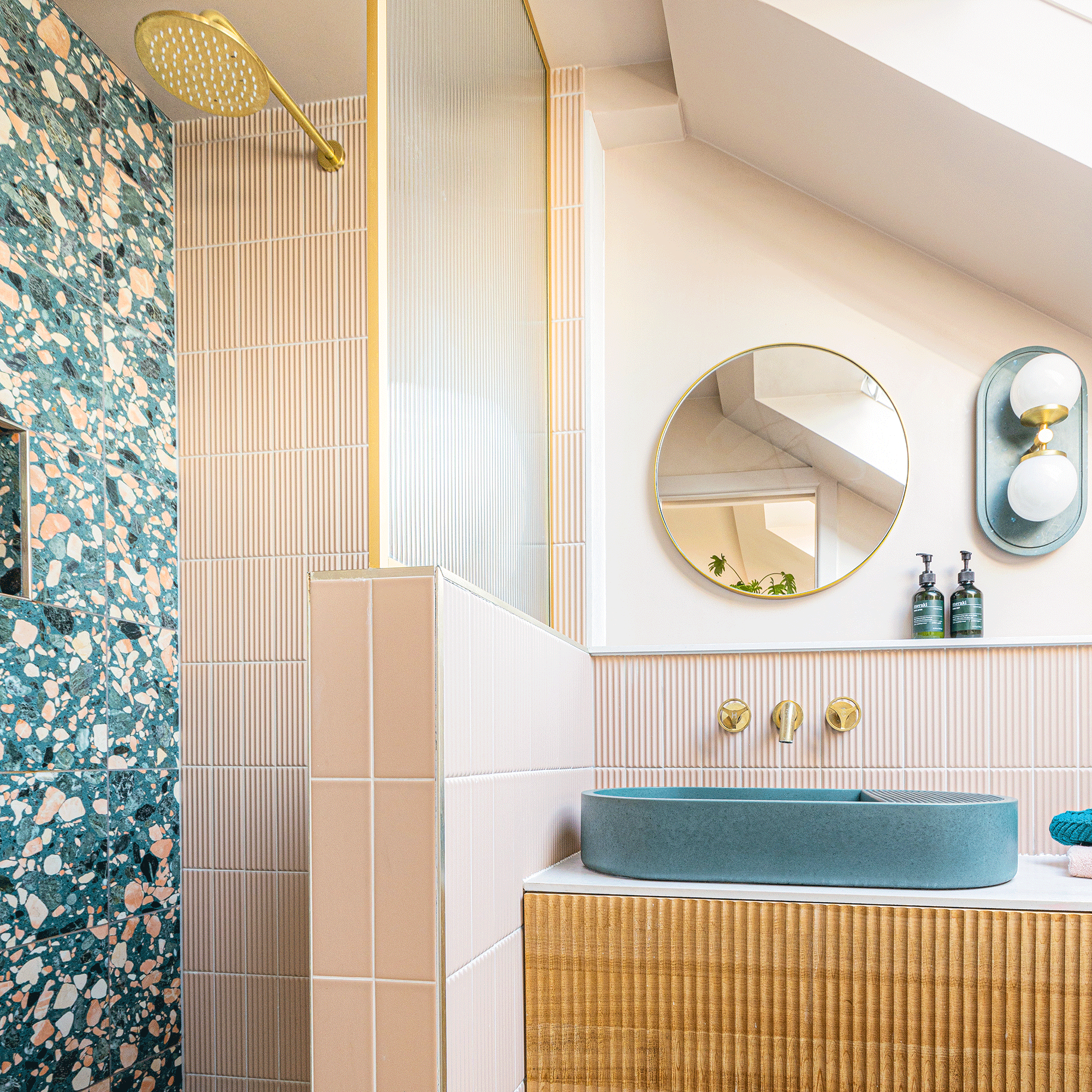 Pink bathroom with terrazzo shower wall and blue sink
