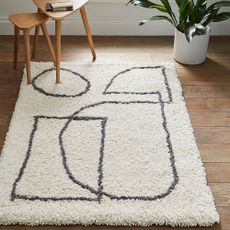 Home Essentials Artisan Rug on wooden floor with wooden side tables and plant