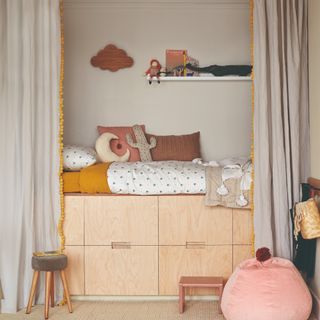 A beige-painted children's room with a storage cabin bed and curtains that can hide the sleeping area and its clutter