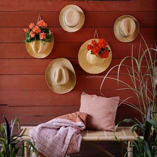 red wooden garden wall with straw hat planters