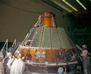 Spacecraft 12 (for AS-204 mission, later renamed Apollo 1) looking toward Y-axis during installation of heat shield. Note uprighting system compressor in aft bay, at right, and Reaction Control System (RCS) valve module panel, center of photo.