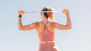 a photo of a woman stretching a resistance band behind her back