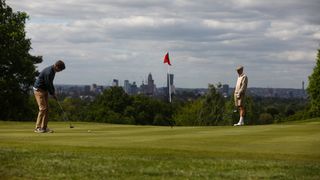 Amateur golfers play with the London skyline in the distance