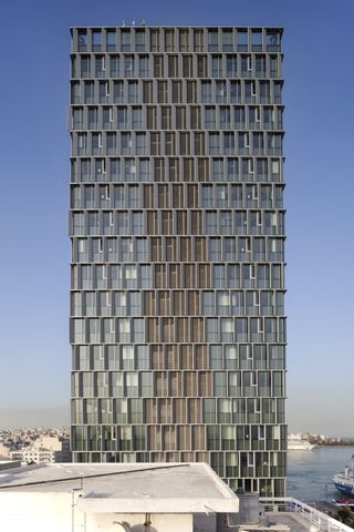 Piraeus Tower, a high rise in Athens with its renovation works completed by PILA, seen in hero glory, gleaming facade and slanted fin shading