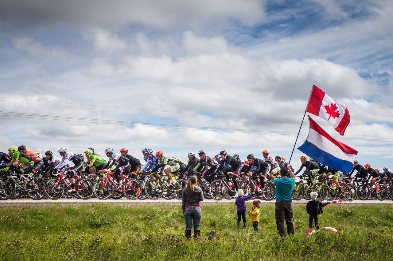 Roadside fans wave as the Tour of Alberta passes by.