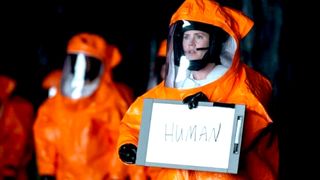 Amy Adams as Louise Banks holding up a sign saying humans during the alien movie, Arrival.