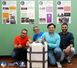 Shown with their experiment packed for launch, READI FP team members from left to right, Michele Cioffi, program manager; Fabio Peluso, honorary member of MARSCenter scientific committee; Marco Fabio Miceli, system and test engineer; and Pasquale Pellegrino, test engineer from Aerospace Laboratory for Innovative components (ALI) S.C. a r.l. in Italy.