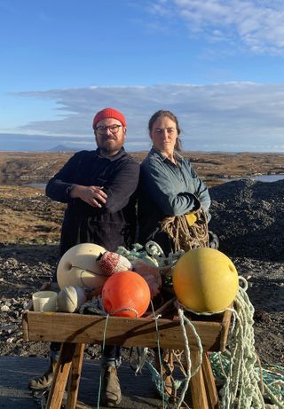 Banjo Beale poses alongside decorator Lisa McKenna behind a knee-height table festooned with ropes, buoys and other seafaring equipment