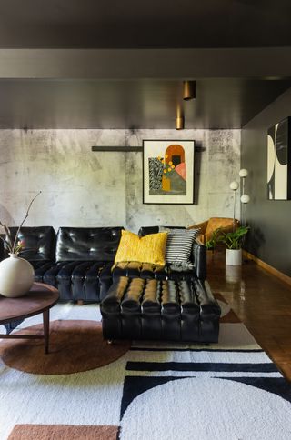 modern living room with leather sofa geometric monochrome rug low ceiling and cement style feature wall