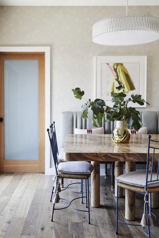 An eclectic dining room with a banquette and a wooden dining table as the focal point