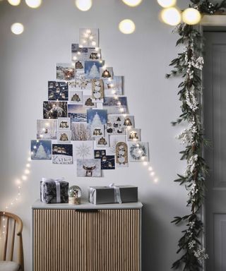 A Christmas card 'tree' with fairy lights draped in triangular shape