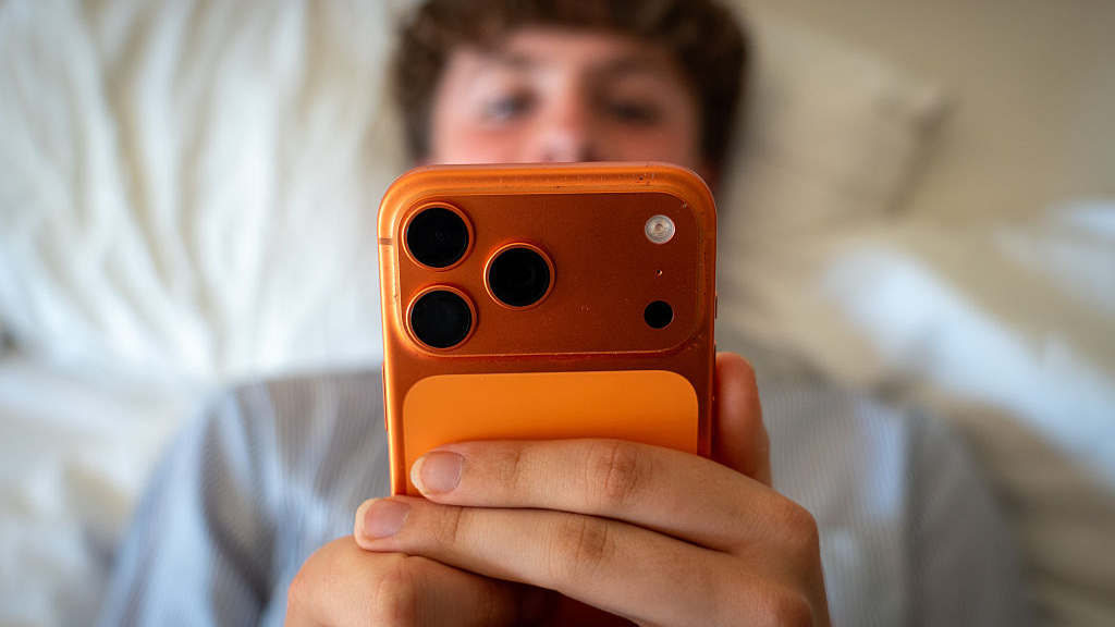Boy using an iPhone 17 Pro in bed