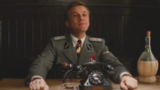 Christoph Waltz sits proudly in front of a telephone in Inglourious Basterds.