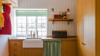 utility room with yellow cabinets, a butler sink, open shelving and laundry area