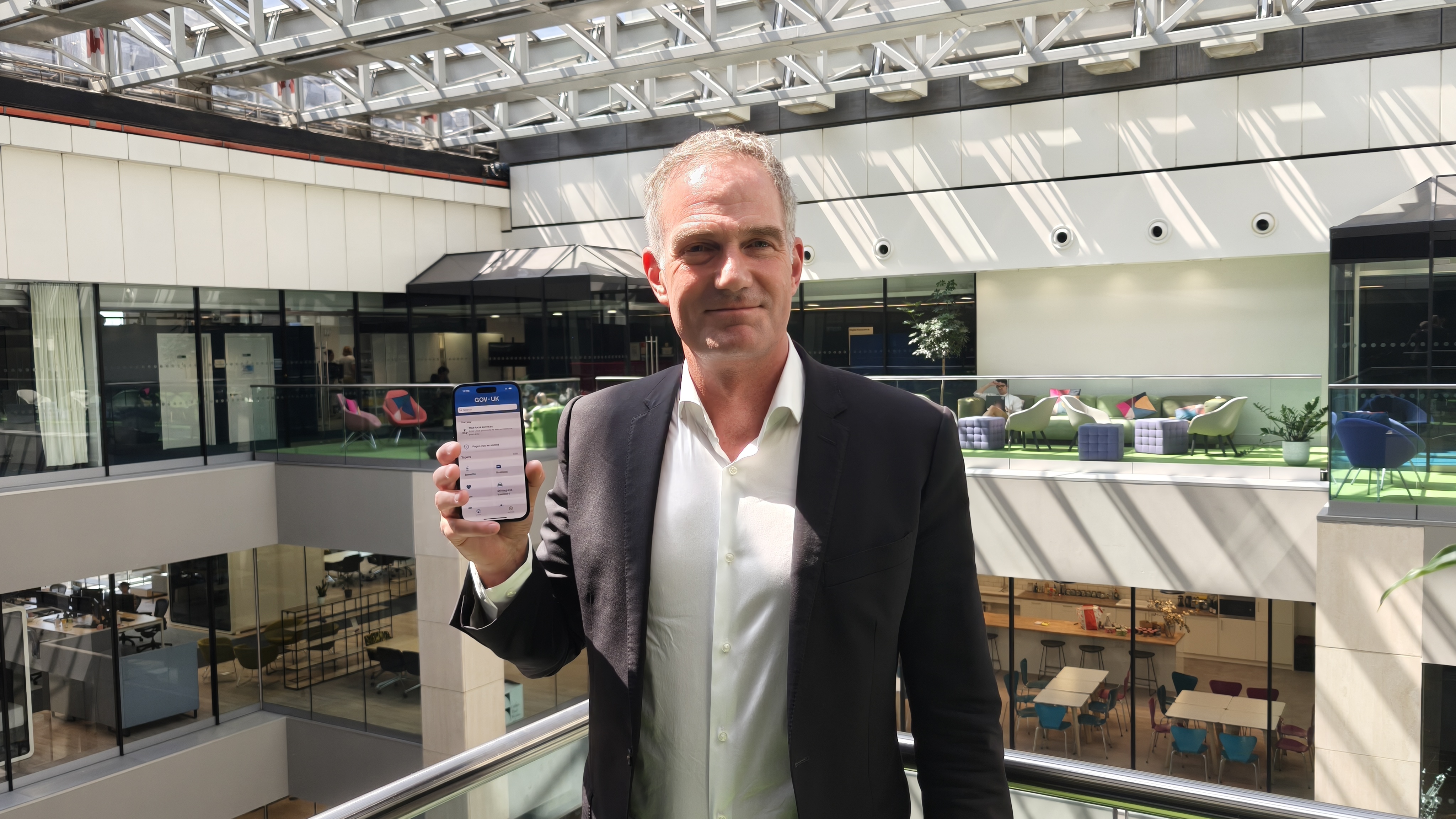 Technology secretary Peter Kyle holding an iPhone running the Gov.uk app