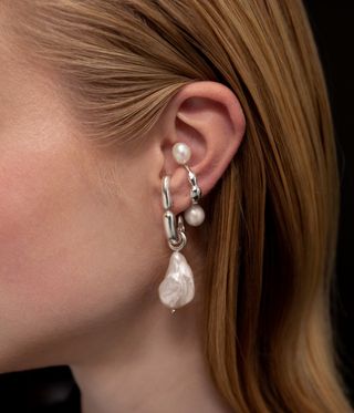 Woman wearing silver pearl earings over her ear