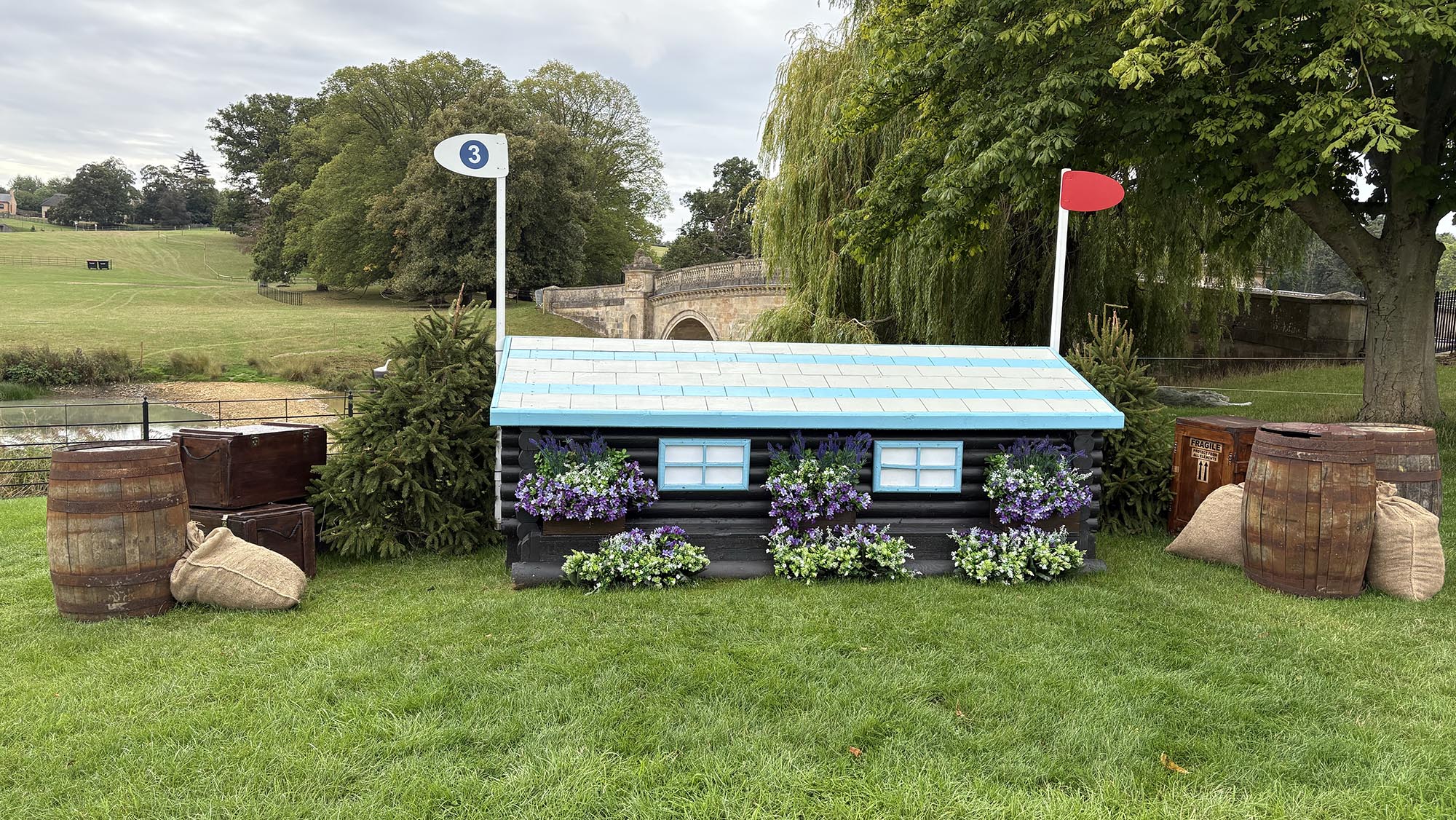 Blue and white house fence with water behind on the Burghley cross-country course 2026