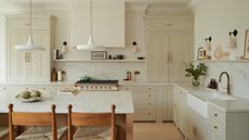 A warm white kitchen with a wood island, brass hardware, and wooden flooring