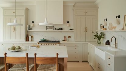 A warm white kitchen with a wood island, brass hardware, and wooden flooring