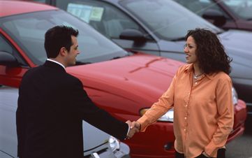 Man and woman shaking hands in a car lot