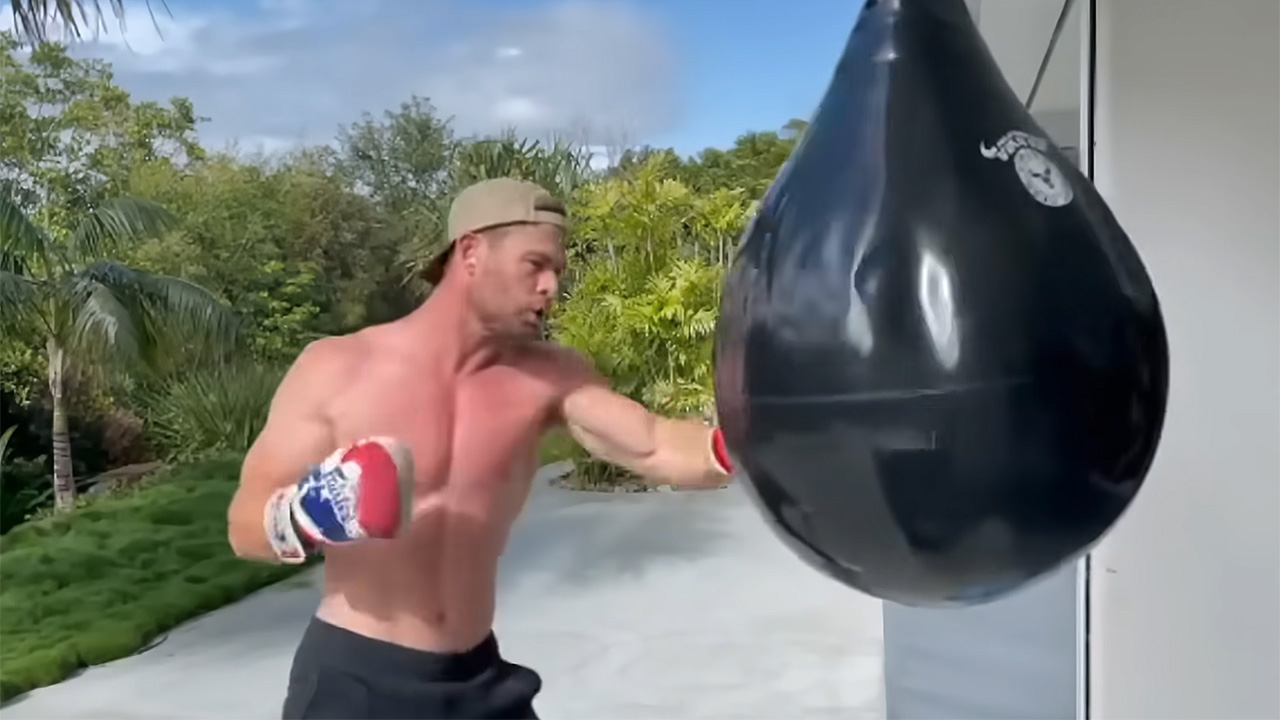 Chris Hemsworth hitting a big black bag to refine his abs.