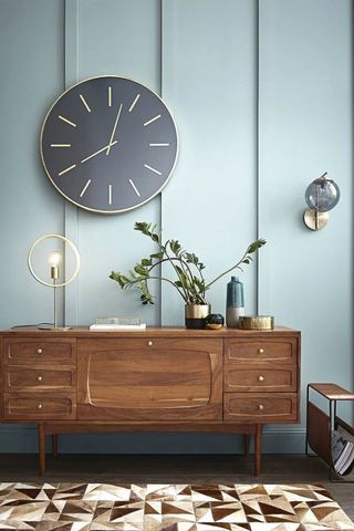 Maisons du Monde Mia-black-and-golden-metal-clock-with-blue-panelled-wall-and-brown-geometric-rug