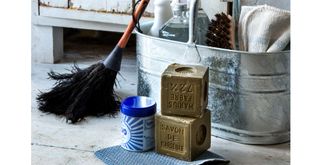 spring cleaning products including dish soap , feather duster and metal mop water bucket on a wooden floor