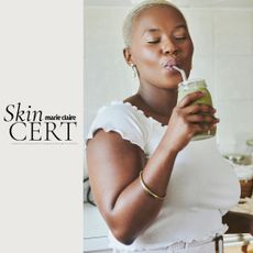 A young Black woman with glowing skin drinking a green smoothie in her kitchen