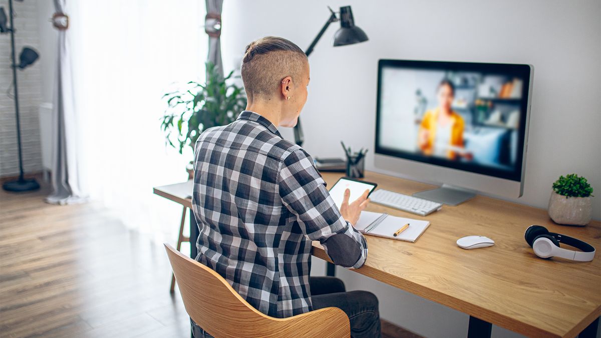 Female job candidate with short hair participating in a video call interview while using AI tools on small tablet device out of view of the recruiter.