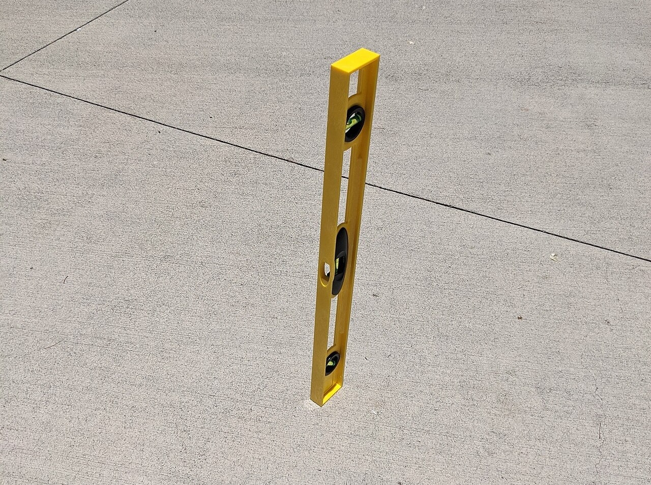 A spirit level sitting on a road and casting no shadow