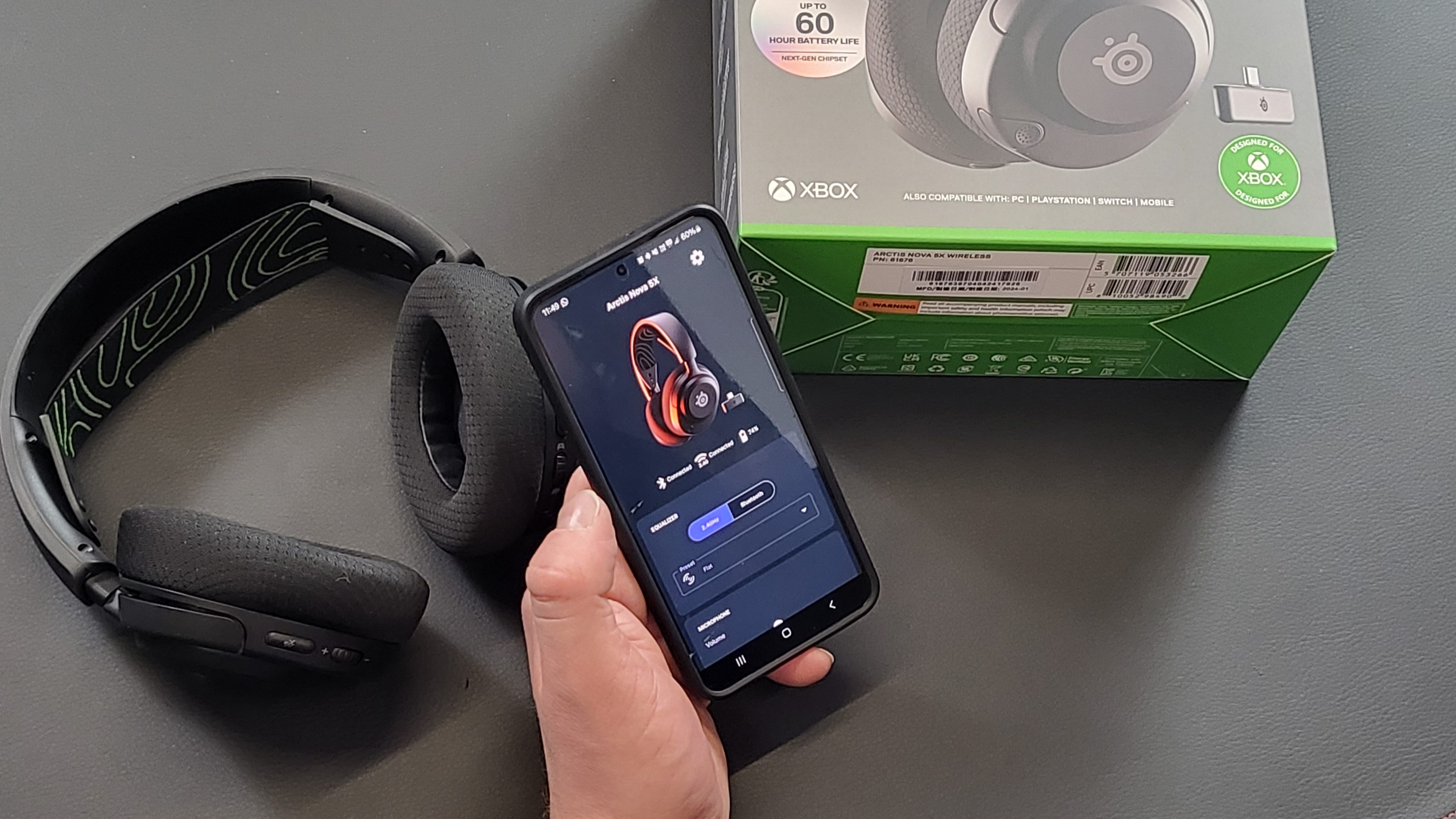 Someone using the SteelSeries Arctis Nova 5 Companion App on a black surface next to the headset