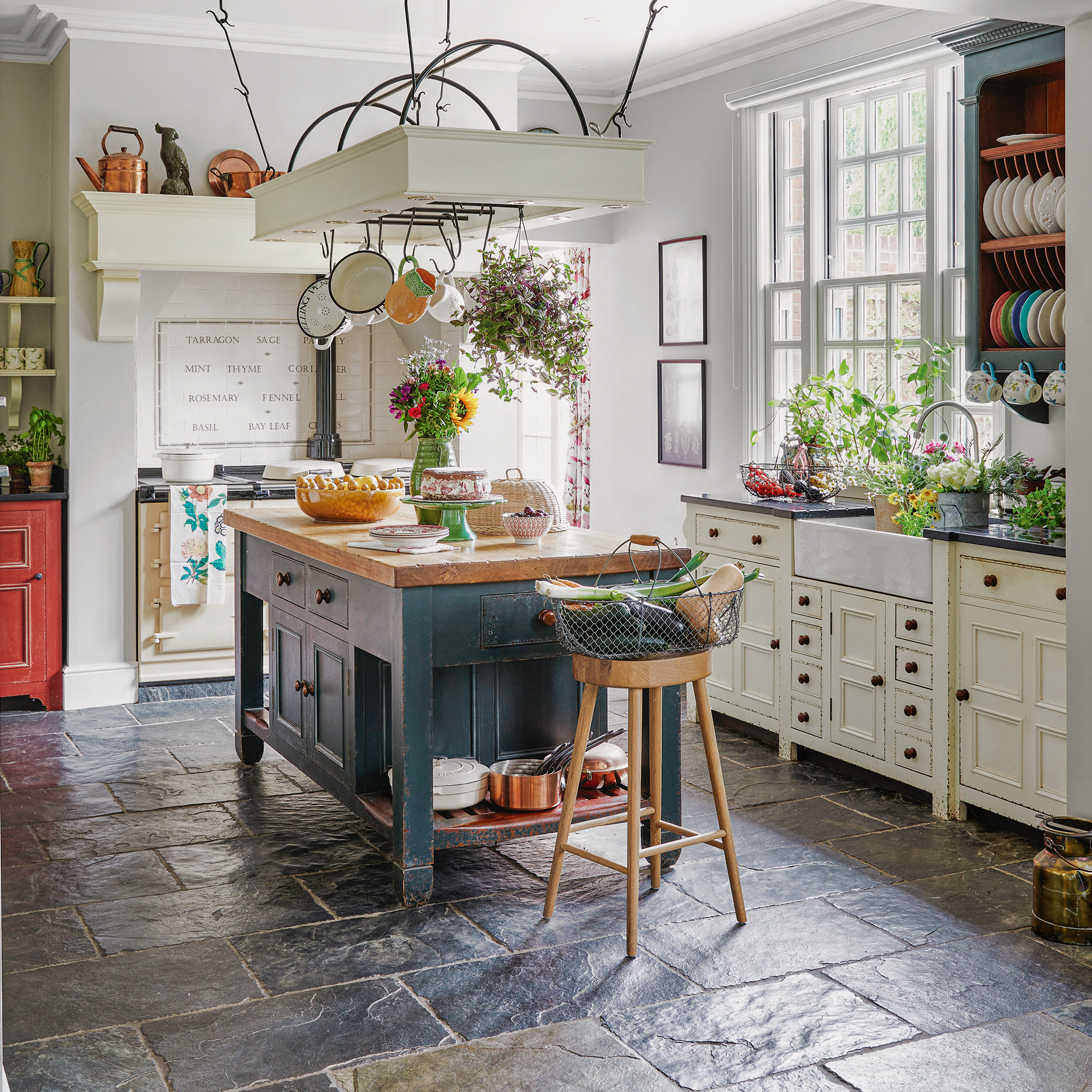 country kitchen with a freestanding island, stone floor tiles, cream units and range cooker