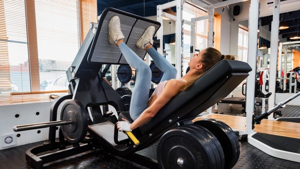 a photo of a woman using a leg press machine