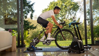 Image shows a person riding a Wahoo Kickr V5 smart trainer which is currently on sale