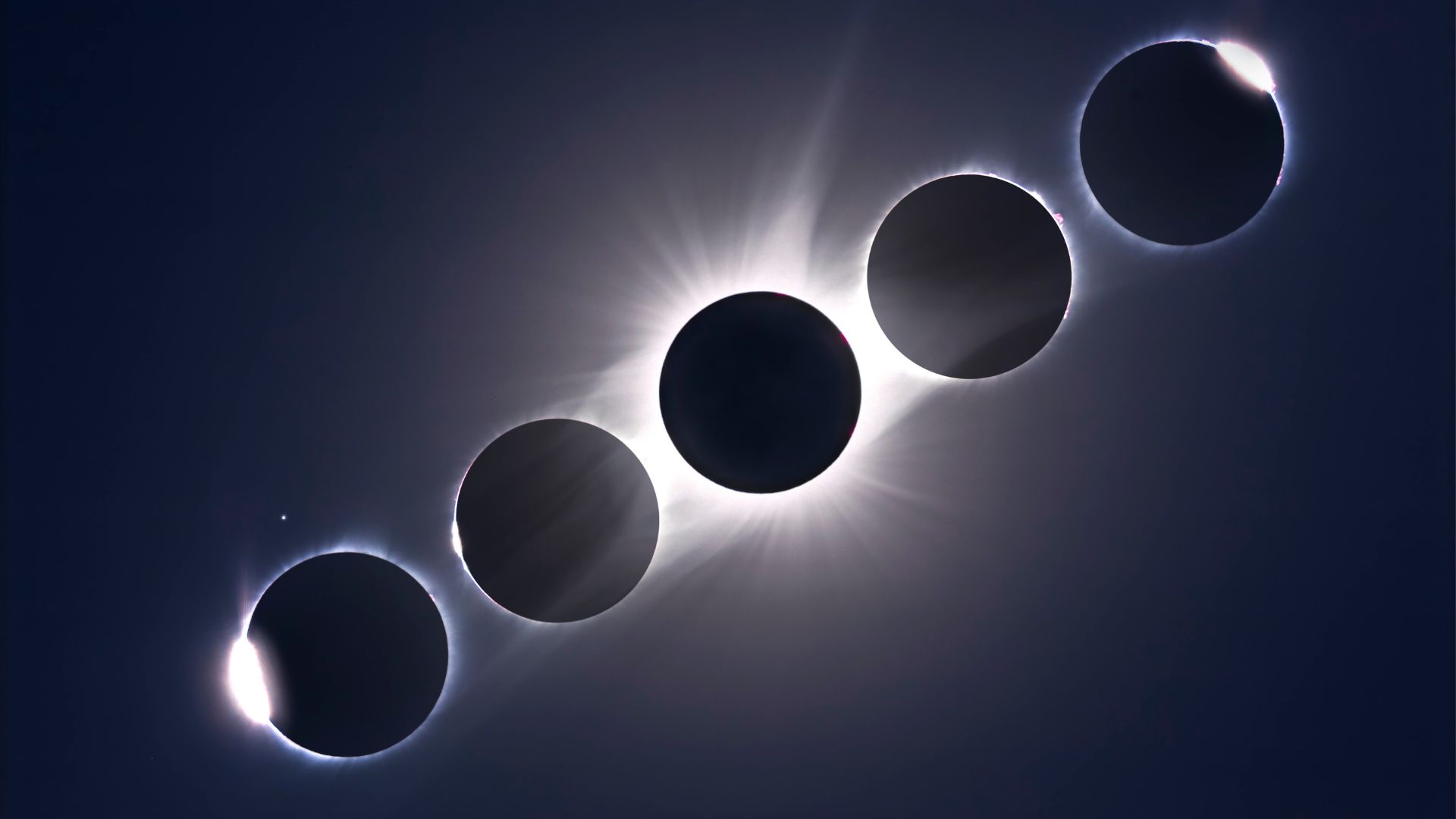 A composite image of 5 sun/moon conjunctions showing the stages of a total solar eclipse arrayed in a diagonal line in a dark sky, with the point of maximum eclipse in the middle. 