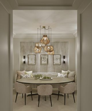 neutral dining with oval table, bench and chair seating, artwork, wall lights and statement pendant