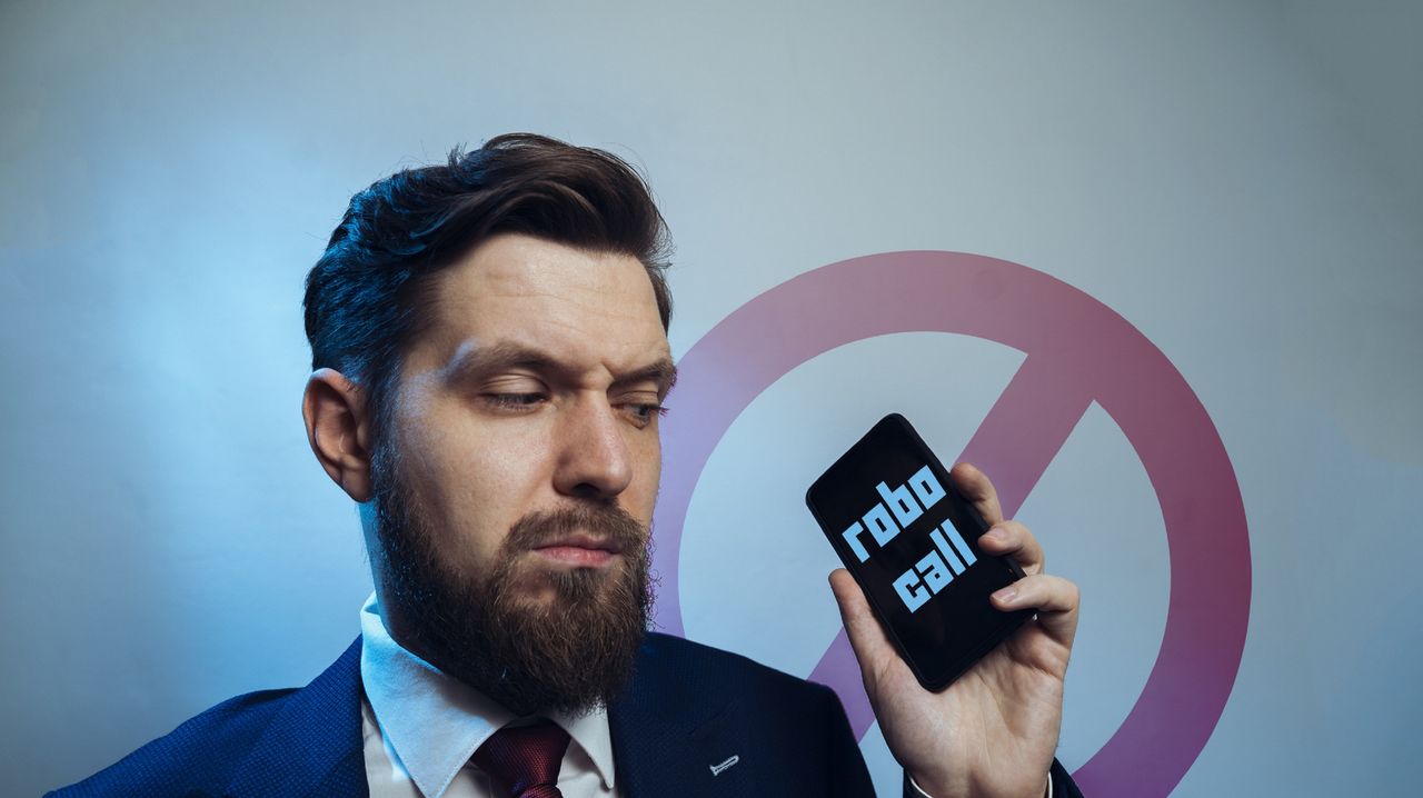 Man looking at phone robocall written on it.