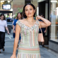 Chase Sui Wonders wearing a colorful striped dress, a pink bag, and silver heels in NYC