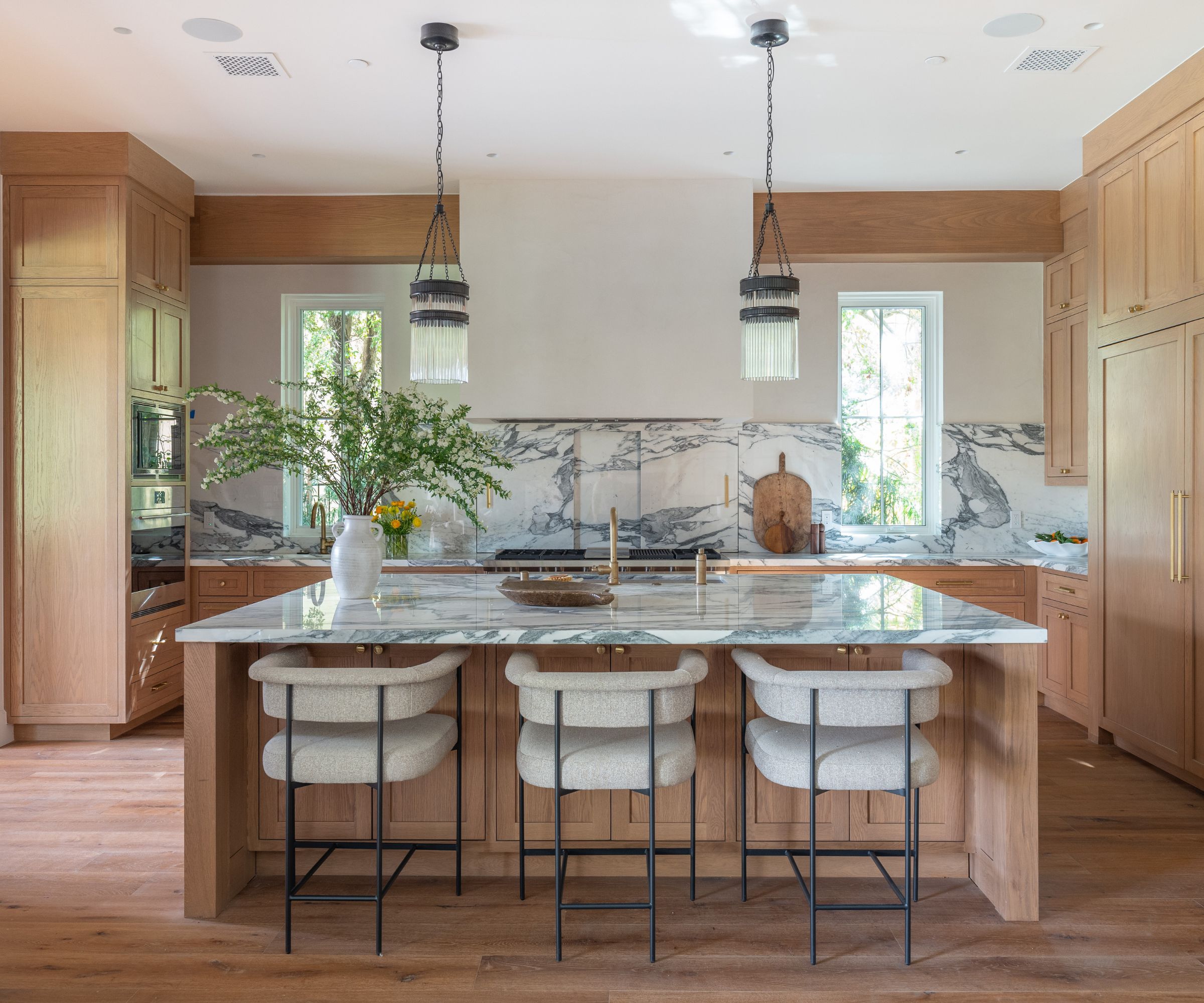A wooden kitchen with marble countertops and a marble splashback with hidden storage