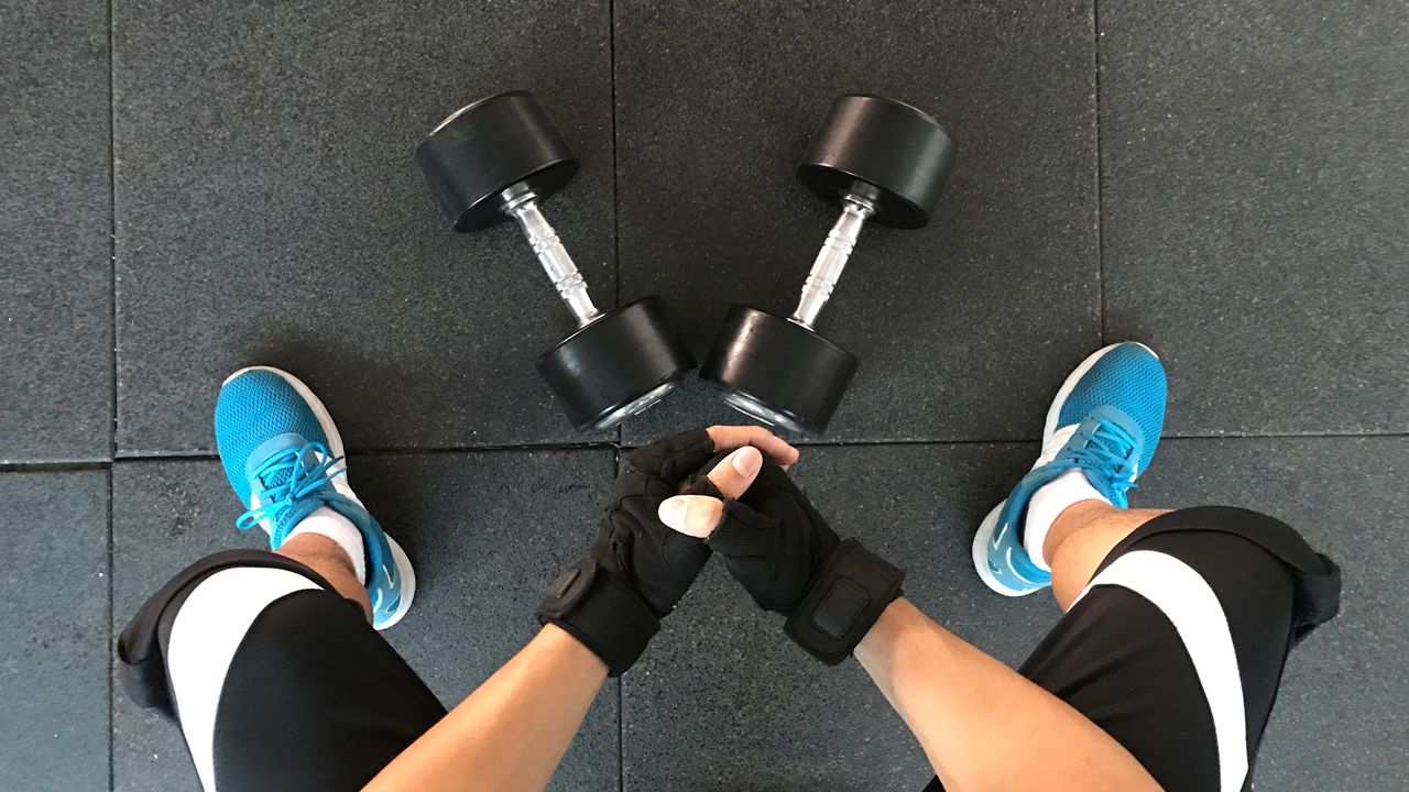 Two dumbbells sit in between a person&#039;s legs