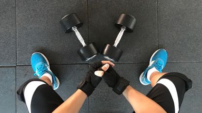 Two dumbbells sit in between a person's legs