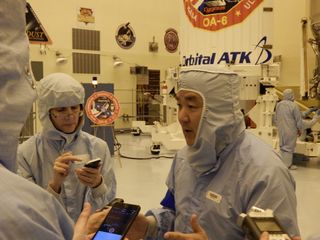 Reporters confer with Orbital vice president Dan Tani in the Kennedy Space Center clean room March 8.