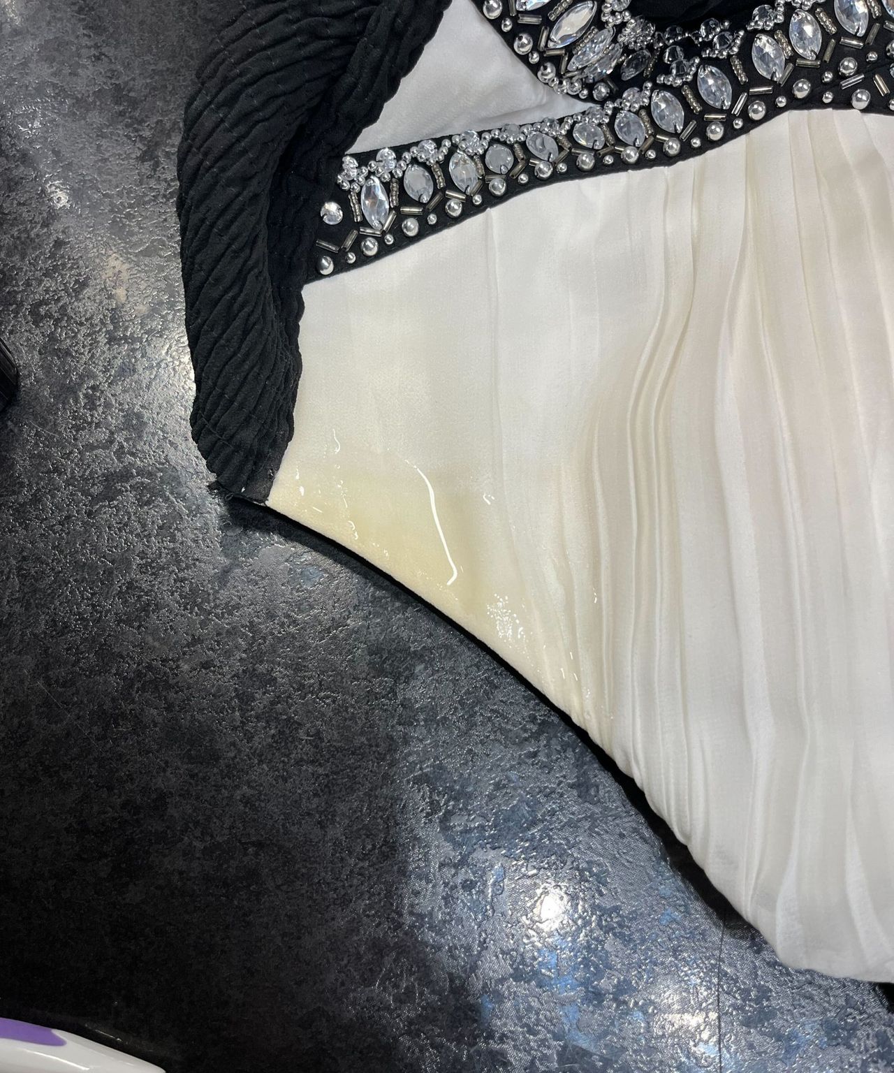 A shiny spot over a yellow stain on the armpit of a cream dress