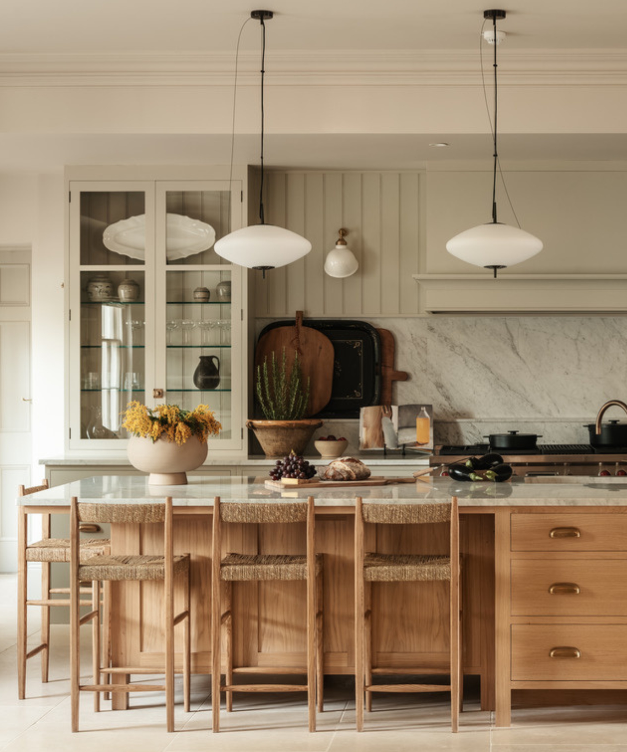 A large kitchen with soft green walls and cabinetry paired with a wooden island