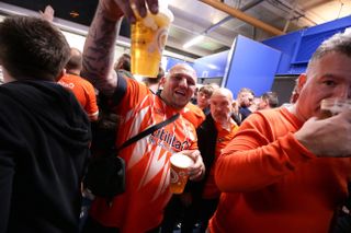 A Luton fan holding a pint of beer on the stadium concourse