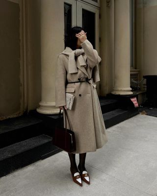 Woman wears beige coat, beige sweater, miu miu shoes