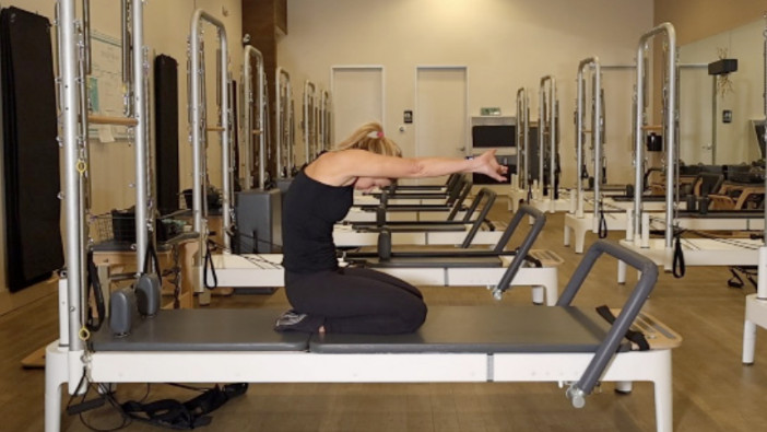 Woman on a Reformer Pilates machine demonstrating an exercise