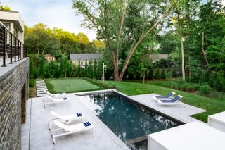 pool landscaping ideas: backyard pool with golf putting green next to it